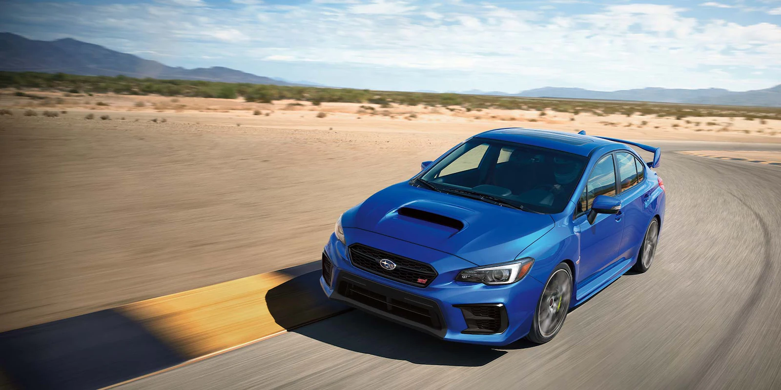 2021 WRX STI driving on a desert highway with mountains in the background.