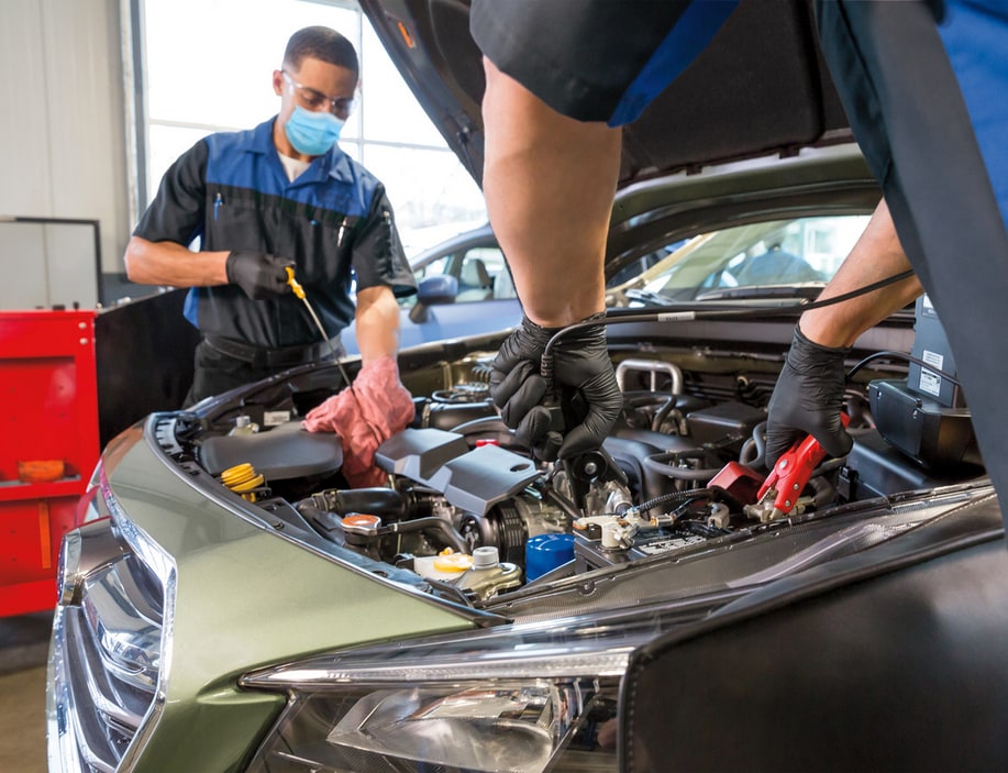 Two Subaru technicians performing maintenance on a Subaru engine compartment
